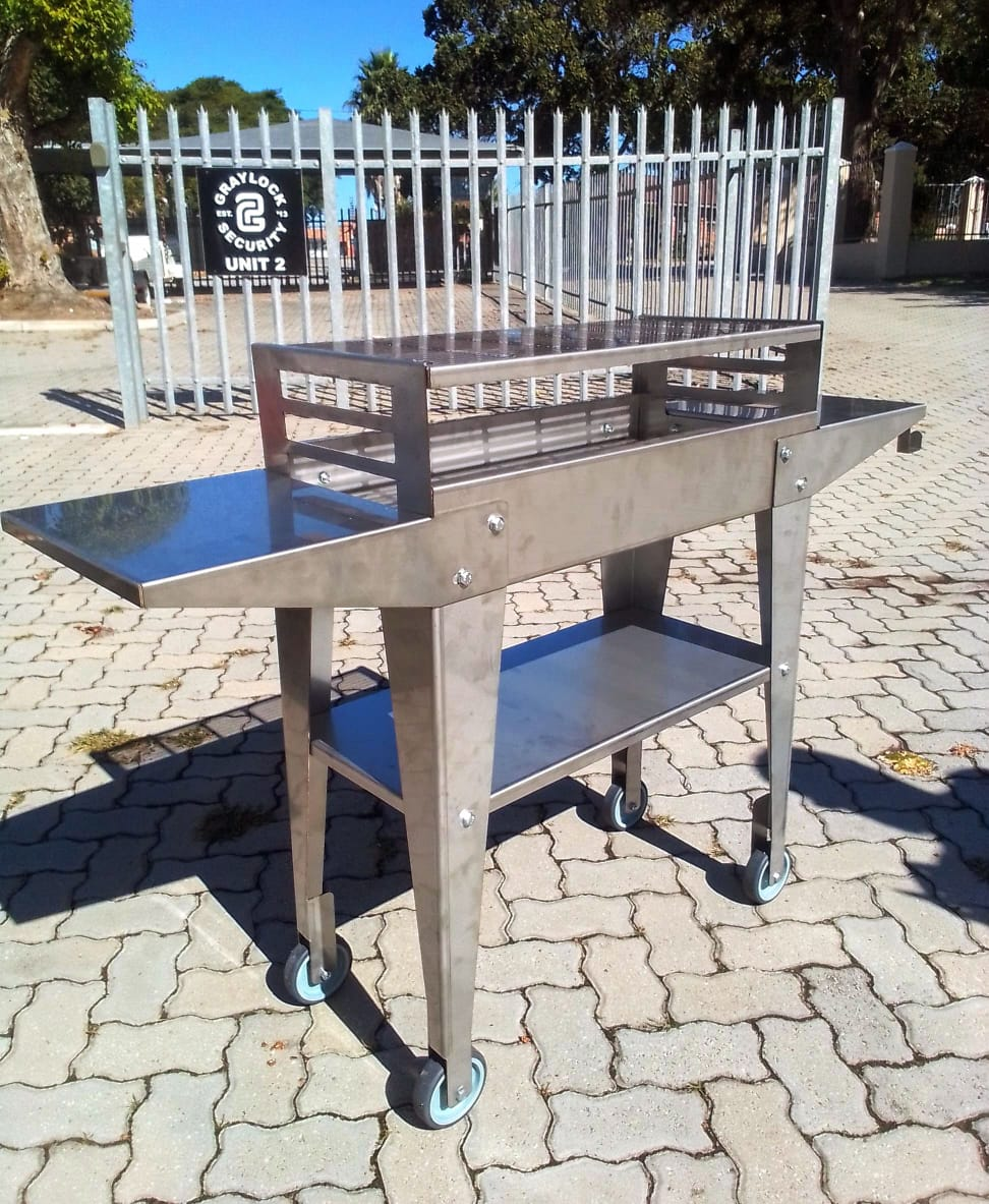 PatioBraai met twee sywerks oppervlaktes, braai rooster, middel rak en vier wiele.
